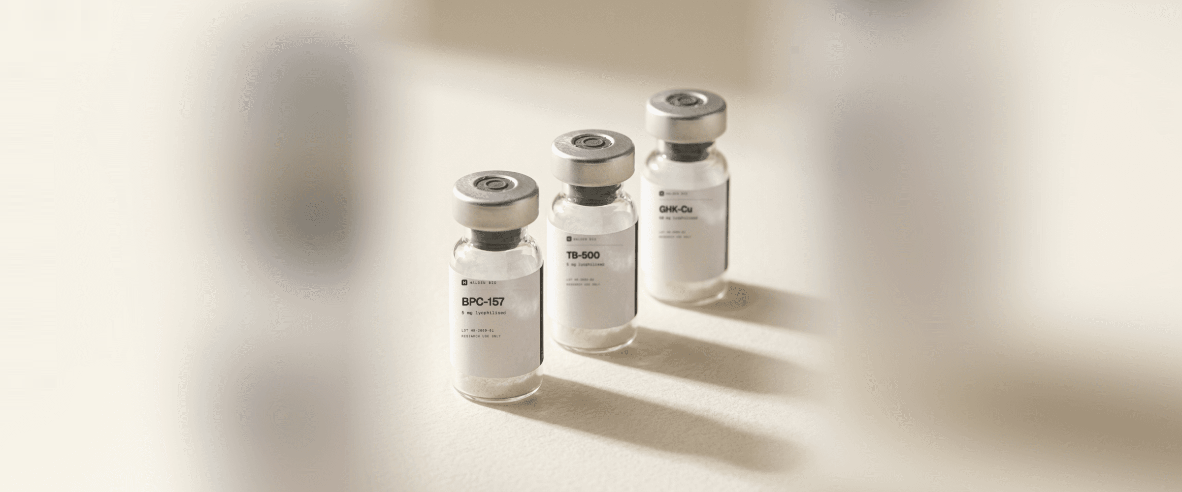 Three glass vials labelled Halden Bio with the compound, quantity and lot number, lyophilised powder visible through the glass
